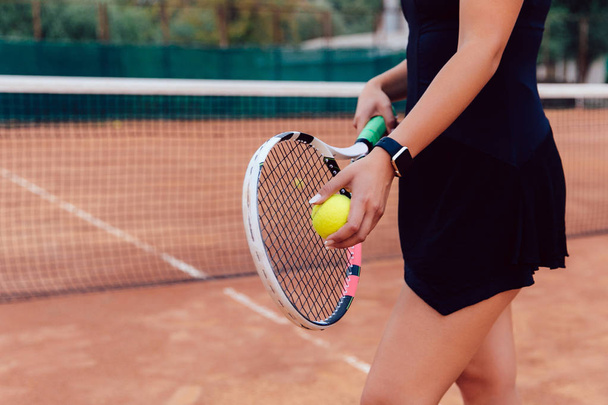 Sportive woman standing with racket and ball on the tennis court. - Foto, imagen