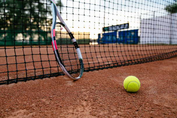 Tennis racket and ball near the net on the tennis court - Foto, afbeelding