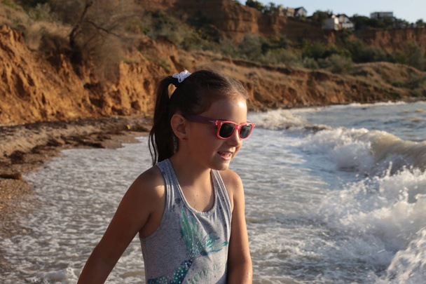 Трохи пустотливої і веселої дівчини вісім років з довгим коричневим волоссям стрибає на хвилях і сміється з задоволенням від літніх канікул
 - Фото, зображення