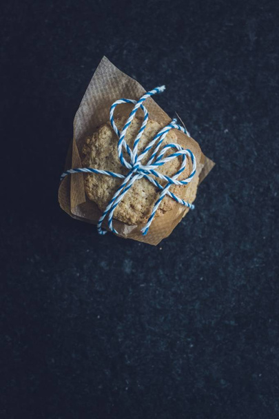 Vertical shot of a tasty cookie wrapped with blue and white lace on a black  surface - Valokuva, kuva