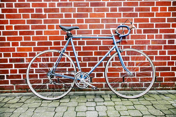 Wide shot of a blue road bicycle leaning on a red wall - Foto, Imagem