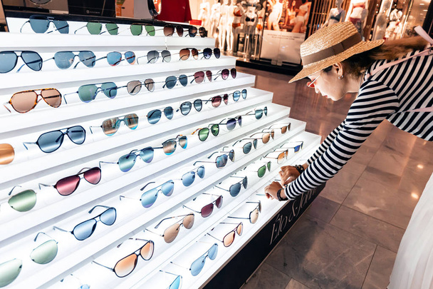 28 July 2019, Paris, France: Happy young woman choosing sunglasses in a store - Foto, Imagem