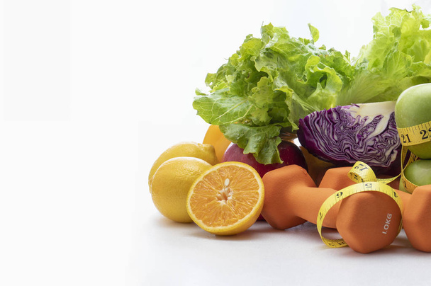 Frisches Obst, Gemüse, Gewichte und Maßband auf weißem Hintergrund. - Foto, Bild