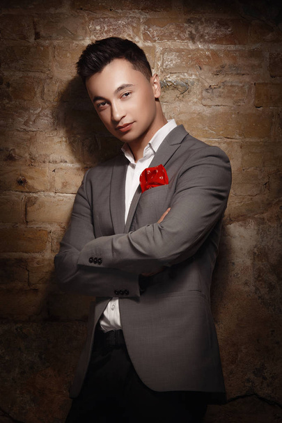 young man wearing suit posing at studio with crossed arms - 写真・画像