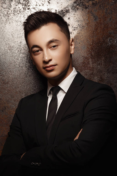 young man wearing suit posing at studio with crossed arms - Фото, зображення
