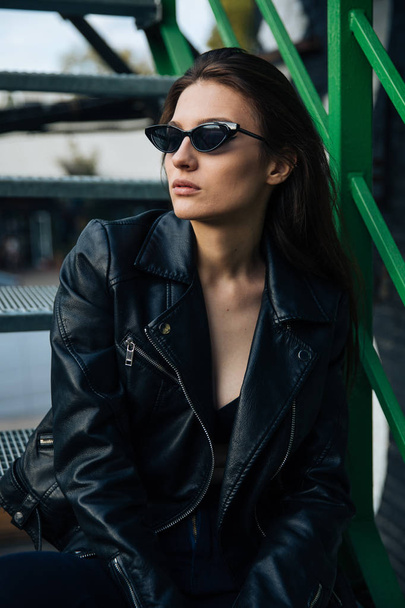 young girl in a leather jacket smokes cigarettes, rock style, cheeky and cute girl street posing style, rock punk lifestyle - Foto, Bild