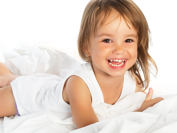 little happy smiling cheerful girl in a bed isolated - Foto, imagen