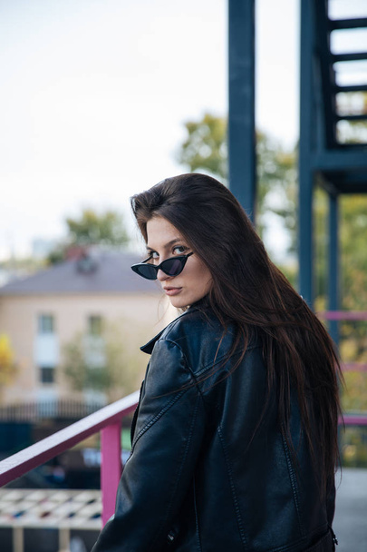 young girl in a leather jacket smokes cigarettes, rock style, cheeky and cute girl street posing style, rock punk lifestyle - Zdjęcie, obraz