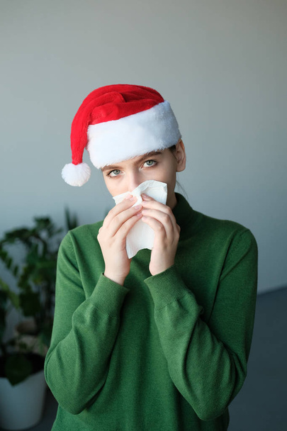 young girl in santa hat blowing nose in home interior - Foto, Imagem
