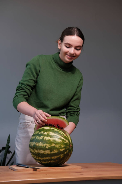 young woman cutting watermelon in home interior - Fotografie, Obrázek