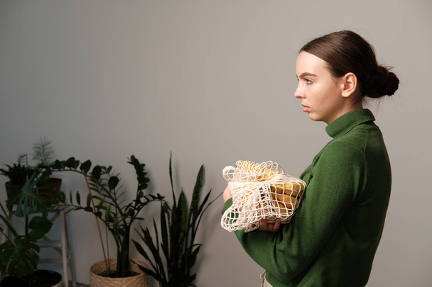 young woman holding string bag with groceries in home interior - Photo, Image