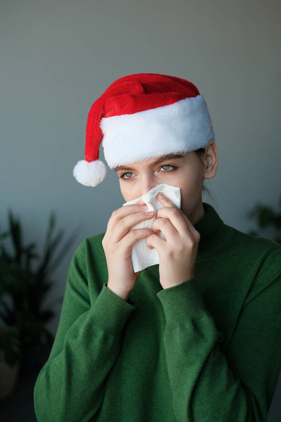 young woman in santa hat blowing nose in home interior - Foto, Imagem