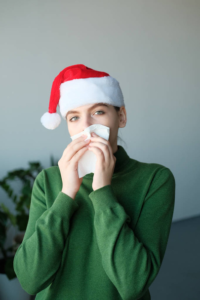 young woman in santa hat blowing nose in home interior - Foto, immagini