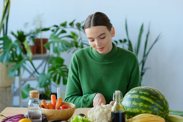 young woman cutting fresh vegetables in home interior - Photo, image