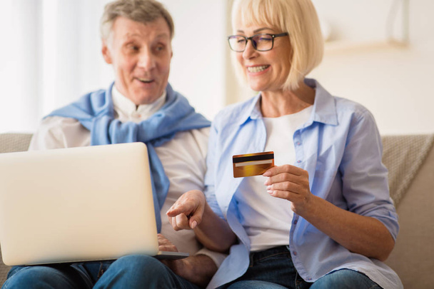 Modern grandparents. Mature couple shopping online on laptop - Foto, afbeelding