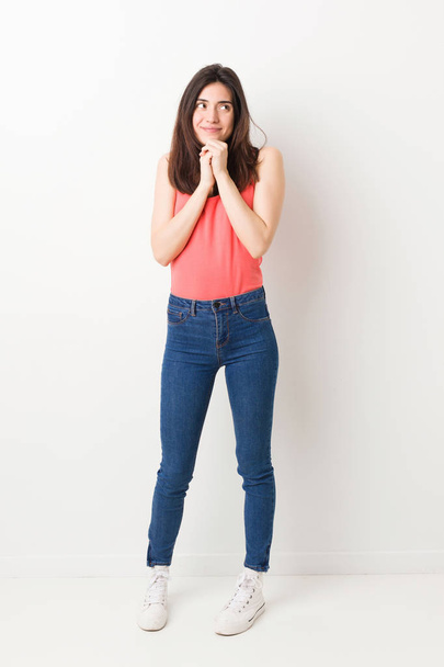 Full body young woman on white background keeps hands under chin, is looking happily aside. - Foto, imagen