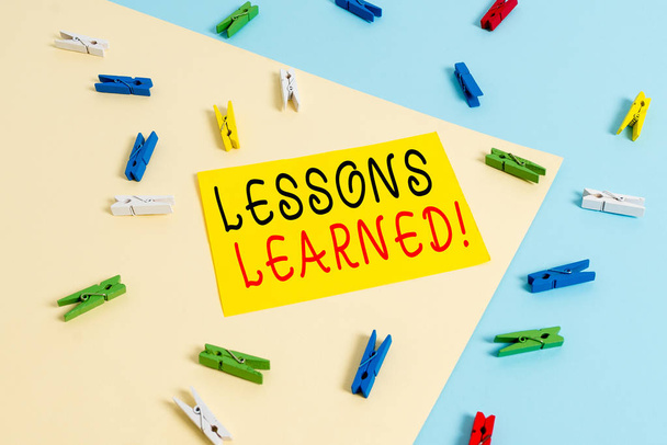 Text sign showing Lessons Learned. Conceptual photo experiences distilled project that should actively taken Colored clothespin paper empty reminder yellow blue floor background office. - Photo, Image