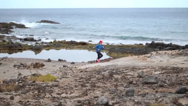 Vrouw loopt langs de steenachtige oever van de Oceaan. Gezonde actieve levensstijl. Slow Motion - Video