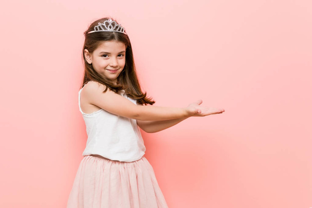 Little girl wearing a princess look holding a copy space on a palm. - Photo, Image