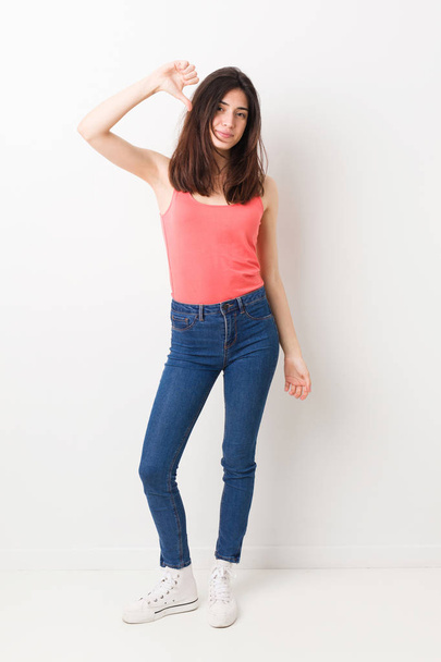 Full body young woman on white background showing a dislike gesture, thumbs down. Disagreement concept. - Photo, image