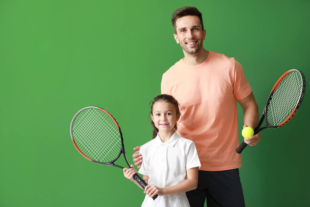 Little girl and her father with tennis rackets on color background - Fotoğraf, Görsel