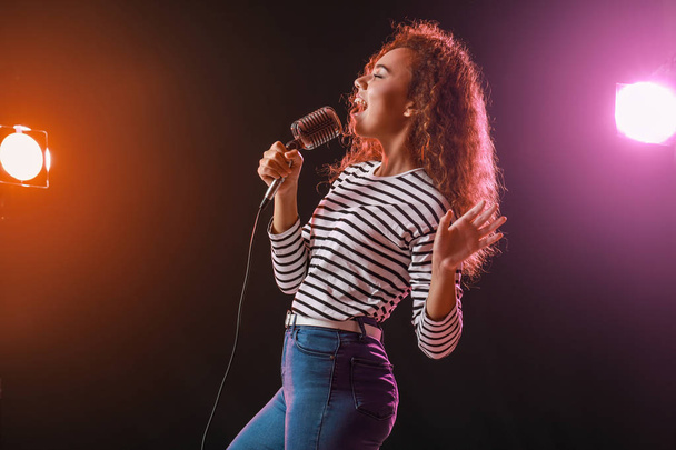 Όμορφη αφροαμερικάνικη θηλυκή τραγουδίστρια με μικρόφωνο στη σκηνή - Φωτογραφία, εικόνα