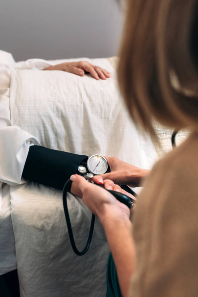 Caregiver checking blood pressure to a senior woman - 写真・画像