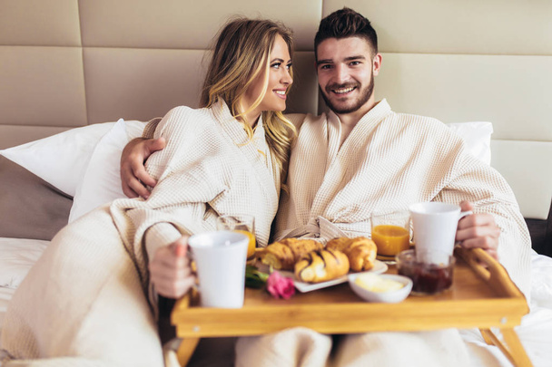 Joven pareja feliz desayunando en habitación de hotel de lujo
 - Foto, imagen