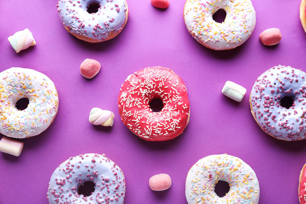 Different tasty donuts with candies on color background - Φωτογραφία, εικόνα