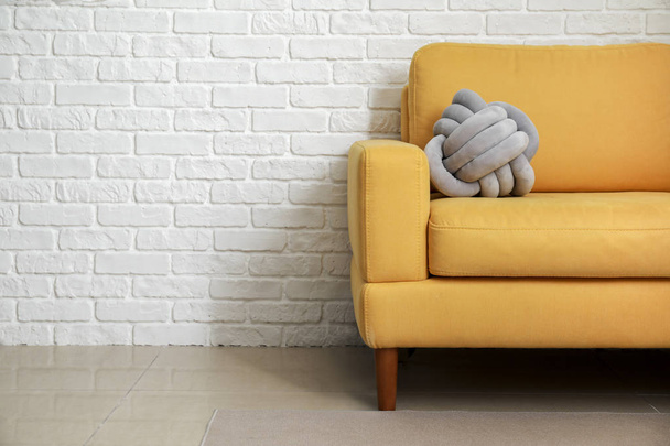 Soft armchair with stylish pillow near white brick wall - Foto, afbeelding