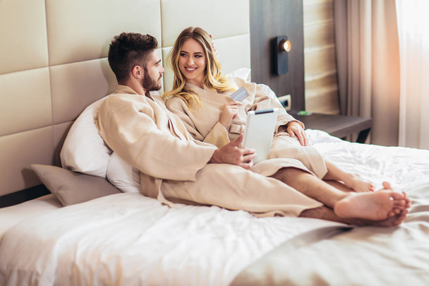 Fiatal boldog pár vásárlás online luxus szállodai szoba.  - Fotó, kép