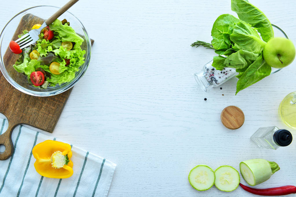 Состав со свежим салатом и ингредиентами на белом столе
 - Фото, изображение
