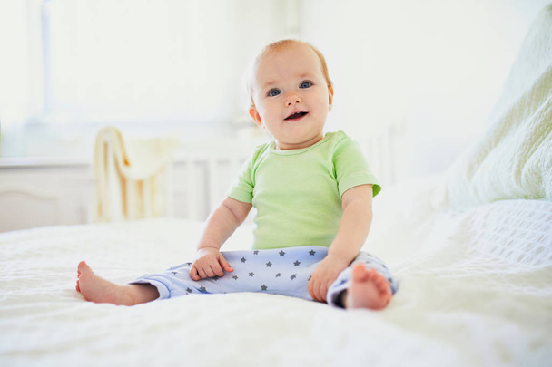 Baby girl sitting on bed and laughing - Photo, Image