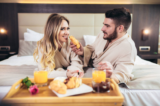 Jong gelukkig paar ontbijten in luxe hotelkamer.  - Foto, afbeelding