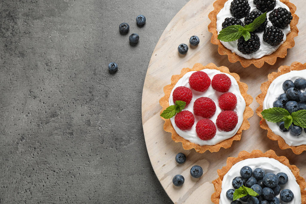 Tarts with different berries on grey table, top view with space for text. Delicious pastries - Foto, immagini