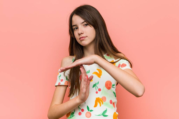 Girl wearing a summer clothes against a red wall showing a timeout gesture. - Photo, Image