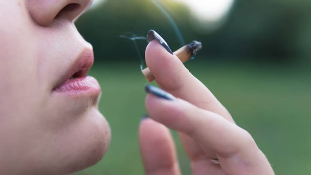 Το νεαρό άτομο που καπνίζει κοινή ιατρική μαριχουάνα σε εξωτερικούς χώρους. Το y - Φωτογραφία, εικόνα