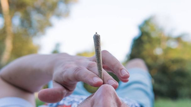 The young person smoking medical marijuana joint outdoors. The y - Photo, Image