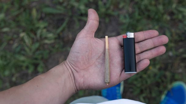 Κοντινό μέρος των αρσενικών χεριών κρατώντας μαριχουάνα, κάπνισμα κανναβιι - Φωτογραφία, εικόνα