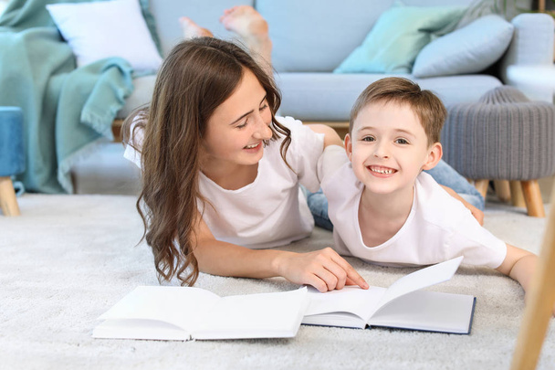 Mały chłopiec i jego starsza siostra czytając książkę w domu - Zdjęcie, obraz