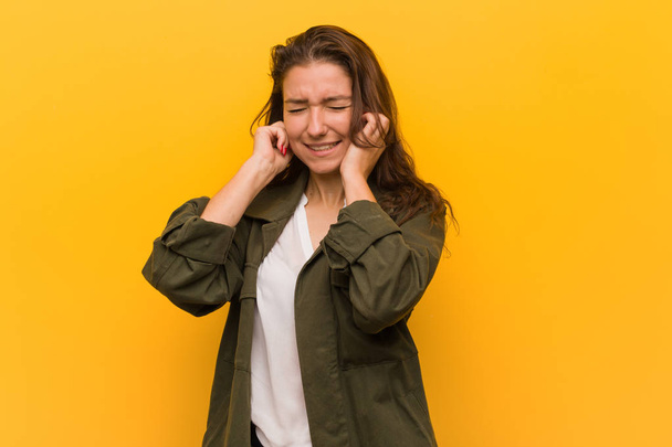 Young european woman isolated over yellow background covering her ears with her hands. - Foto, Imagem