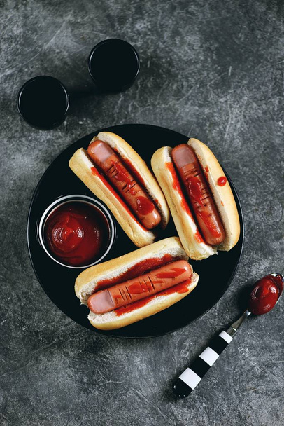Hot Dogs "Finger" in Brötchen und Tomatensauce zum Feiern von Halloween. Nahrung für Halloween. Ansicht von oben.  - Foto, Bild