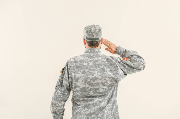 Soldado saudando no fundo claro, visão traseira
 - Foto, Imagem