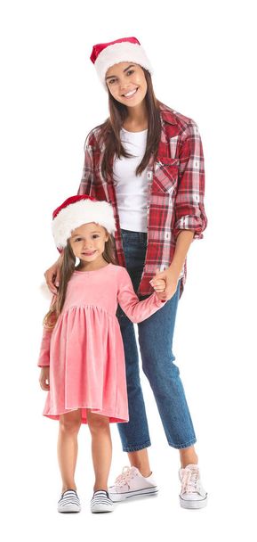 Женщина и ее маленькая дочь в шляпах Санты на белом фоне
 - Фото, изображение