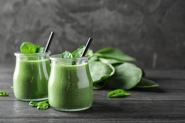Jars of healthy green smoothie with fresh spinach on grey wooden table. Space for text - Foto, immagini