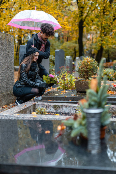 Пара в скорботі на кладовищі восени
 - Фото, зображення