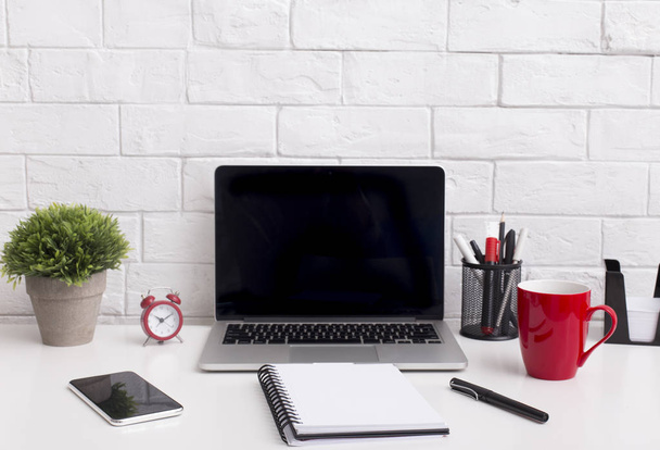 moderner Laptop mit leerem Bildschirm auf Bürotisch mit roter Tasse - Foto, Bild