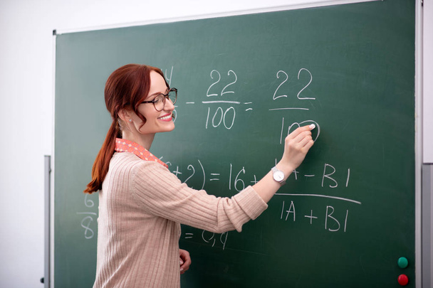 Smiling math teacher explaining new topic to her pupils - Фото, изображение