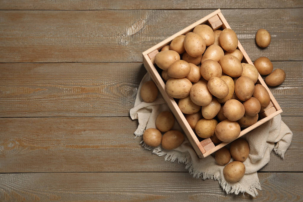 Raw fresh organic potatoes on wooden background, top view. Space for text - Фото, изображение