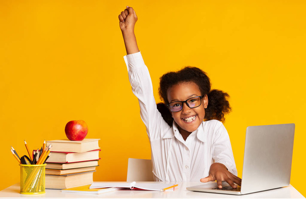 Elementary opiskelija tyttö nostaa käsi istuu Laptop, Studio Shot
 - Valokuva, kuva